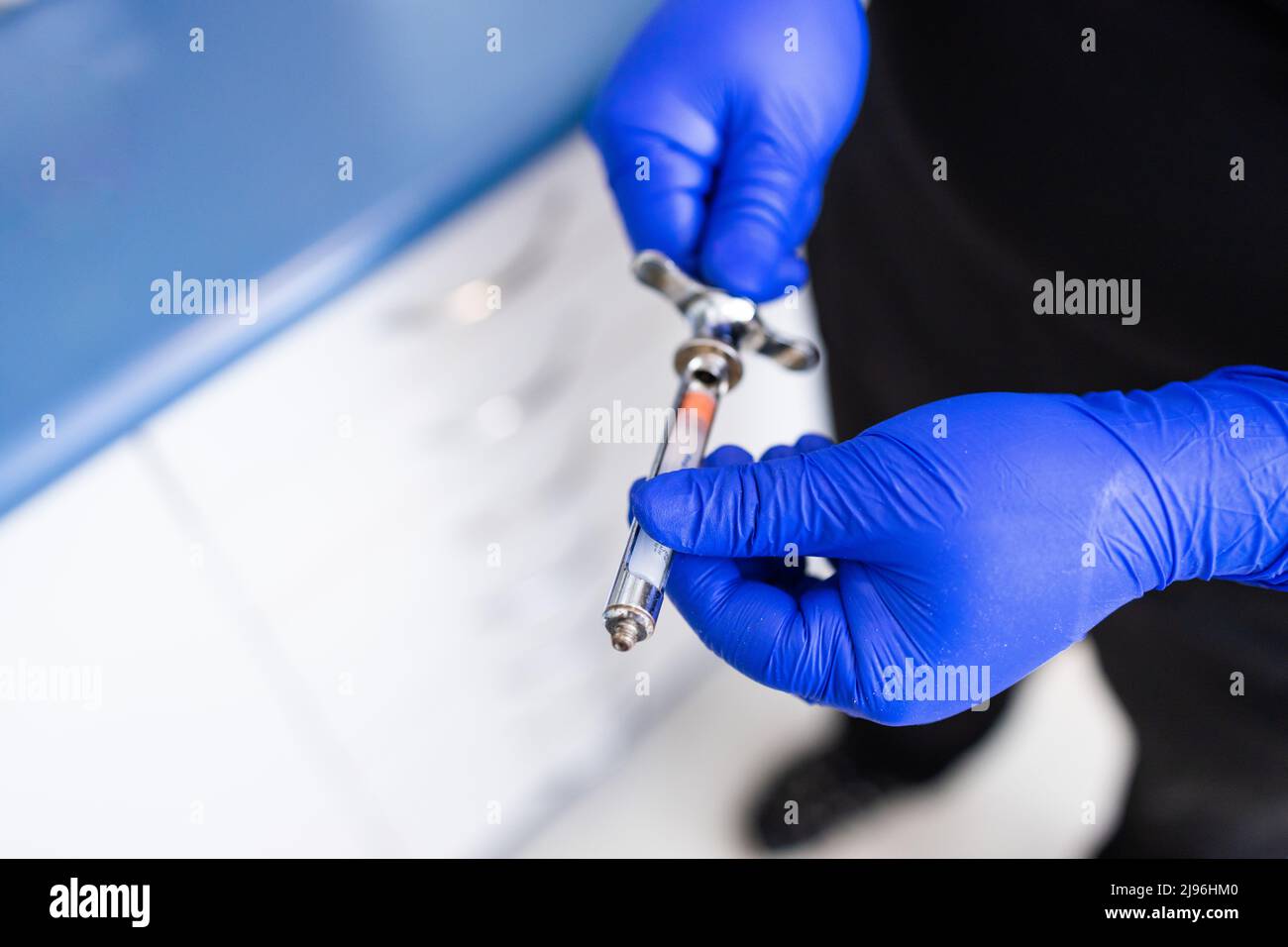 Les mains du dentiste préparent la seringue pour donner l'anesthésie dentaire à son patient. Mise au point sélective. Banque D'Images