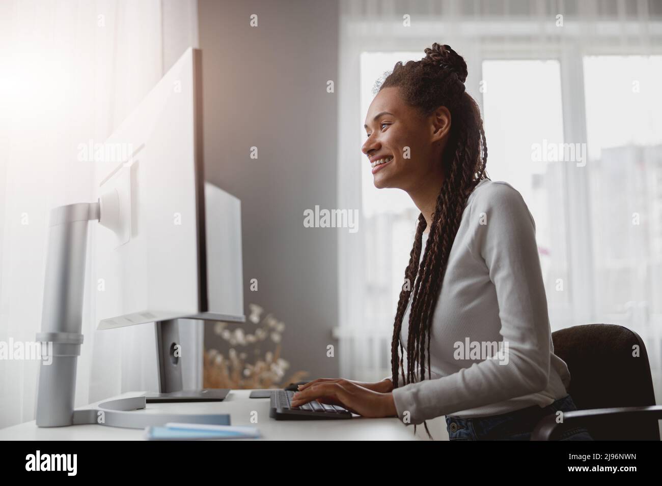 Portrait d'une jeune femme souriante et gaie qui travaille à partir de la navigation à domicile sur un ordinateur Banque D'Images