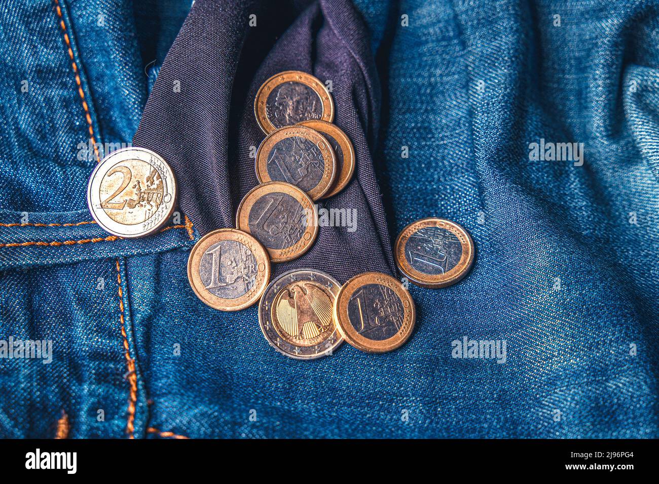 Des pièces de un et deux euros sortent d'une poche intérieure pour jeans Banque D'Images