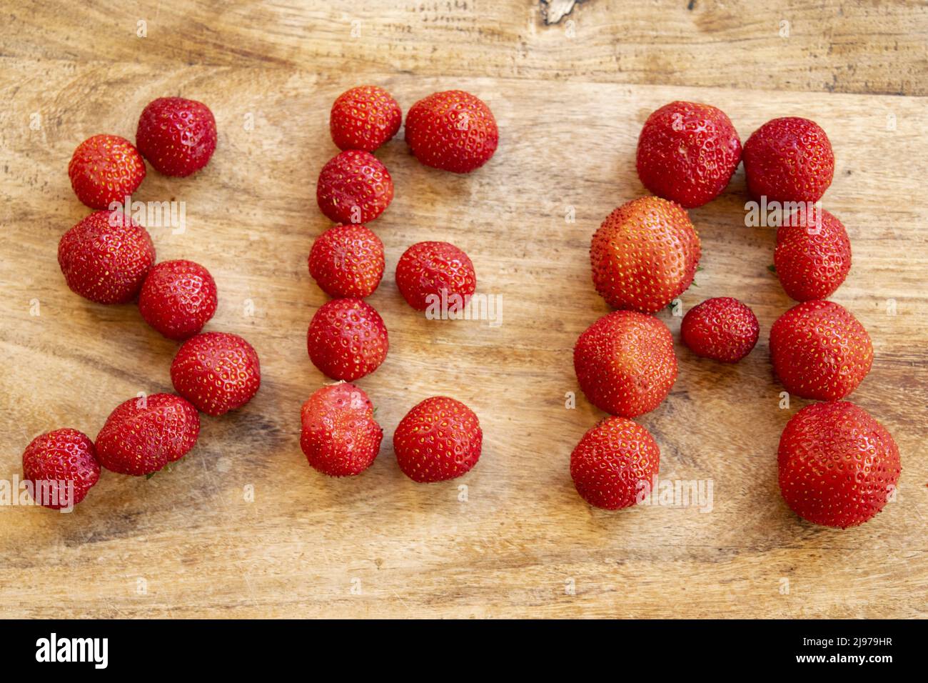 mot fraise écrit avec les mêmes fraises fraîches sur fond de bois Banque D'Images