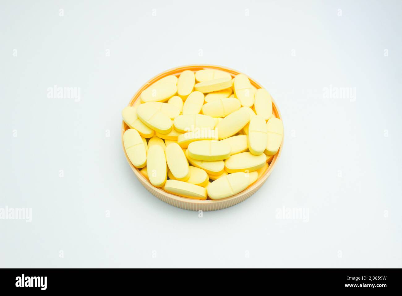 Une pile de comprimés de calcium et de vitamine D complémentaires isolés sur fond blanc Banque D'Images