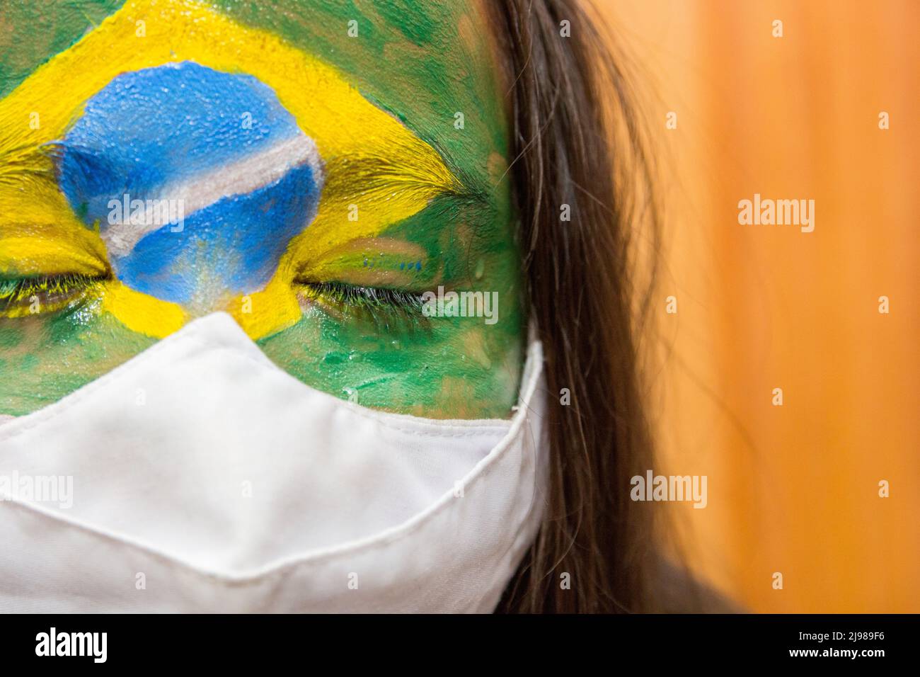 Enfant avec un masque avec son visage peint avec le drapeau du Brésil. Banque D'Images