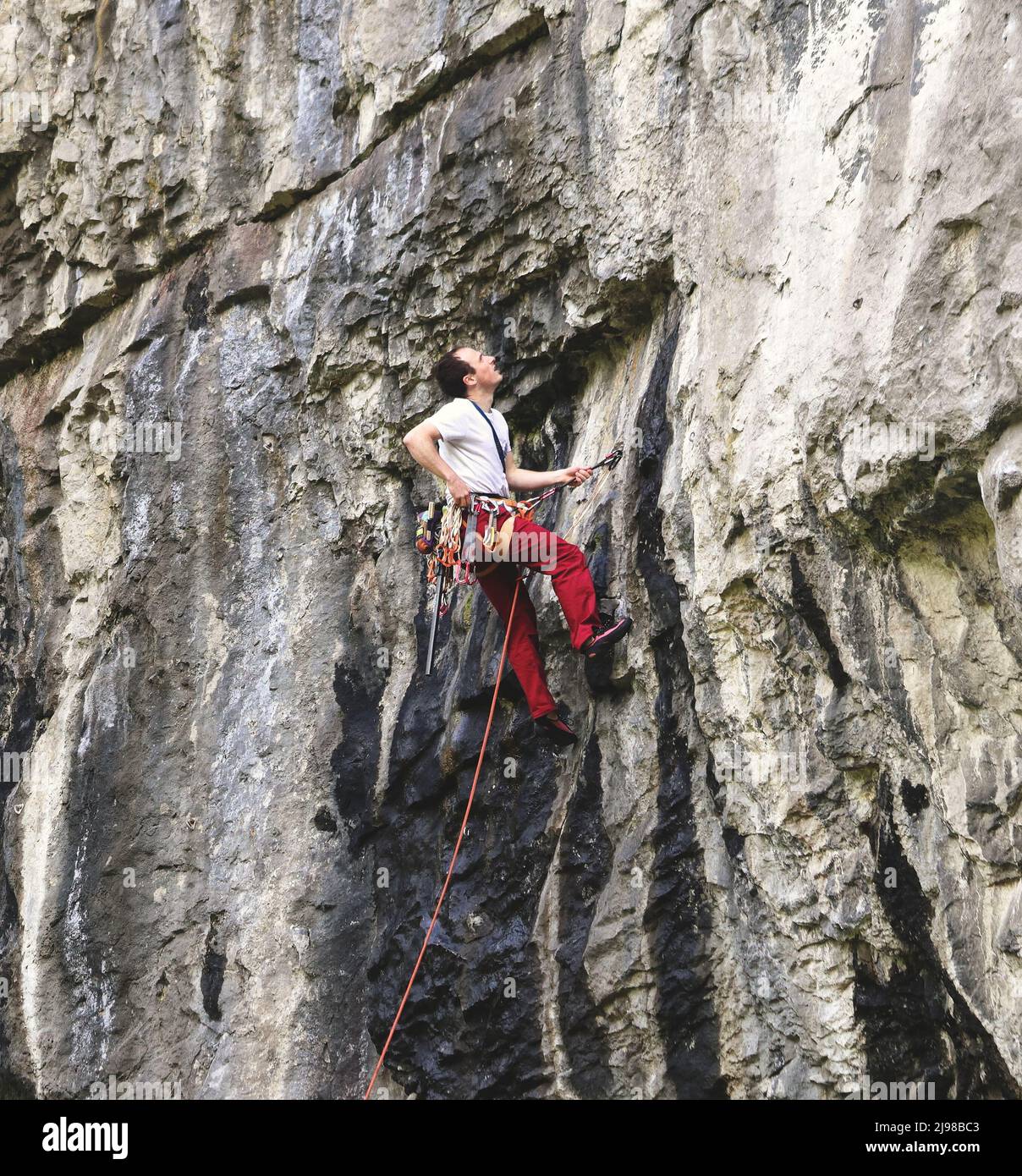 Grimpeur de roche suspendu sur une ligne sur un front de roche dans les Dales du Derybshire en Angleterre Banque D'Images