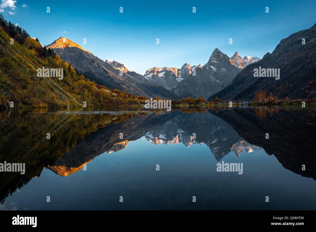 Reflet de la montagne sur le lac. Magnifique paysage avec de hautes montagnes avec des sommets illuminés et le ciel bleu. Vue panoramique sur le lac et les montagnes Banque D'Images