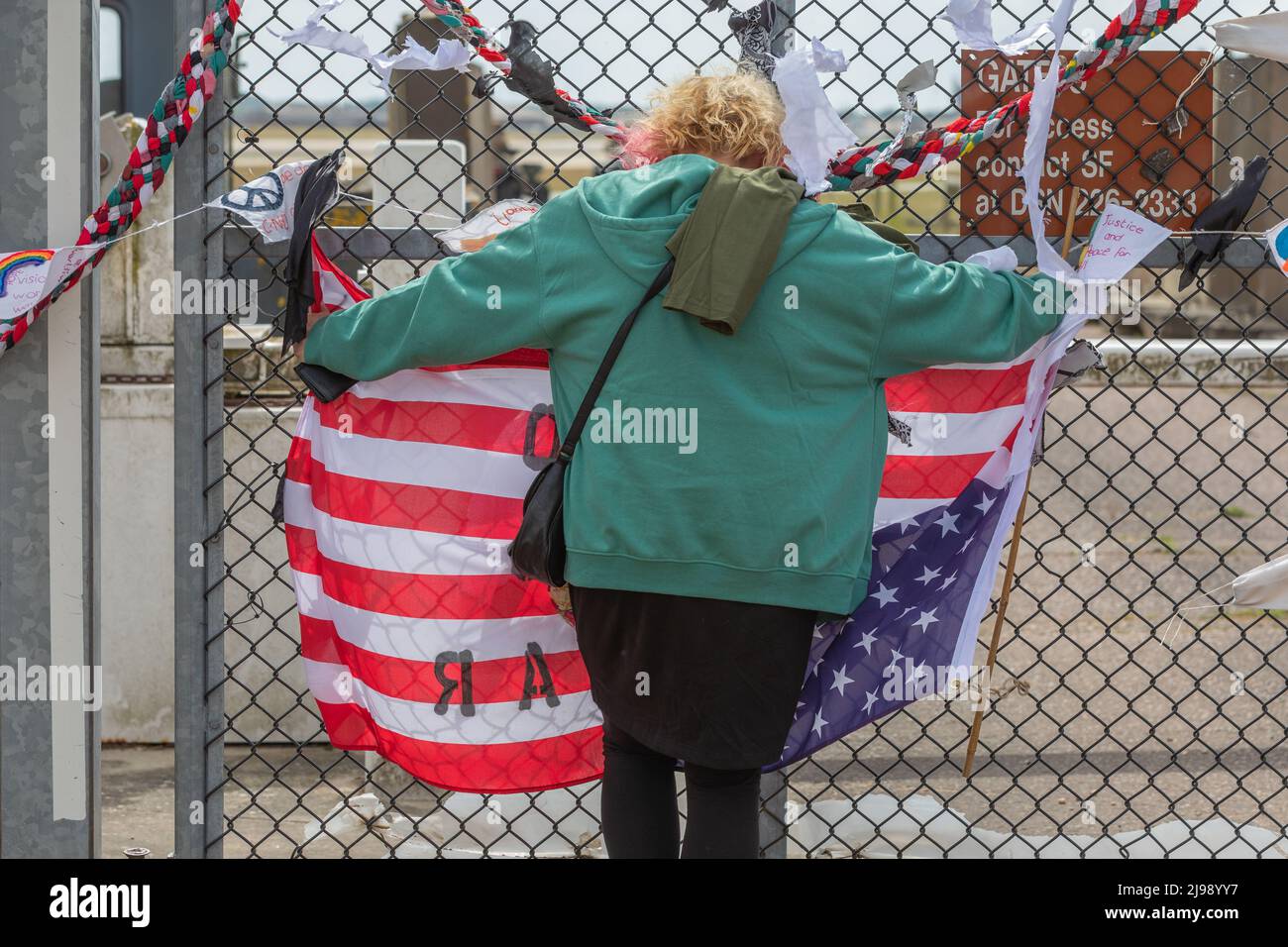 RAF Lakenheath, Suffolk, Royaume-Uni. 21st mai 2022. Un manifestant se tient à la clôture de la frontière et porte un drapeau américain à l'envers. Campagne pour le désarmement nucléaire manifestation devant la base aérienne de Lakenheath à la suite de rapports, les États-Unis se préparent à placer des armes nucléaires sur la base. Penelope Barritt/Alamy Live News Banque D'Images