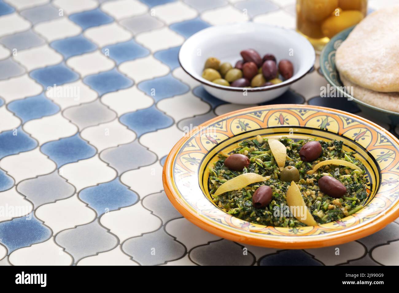 Salade de malow marocaine; les feuilles sont hachées, cuites à la vapeur, puis sautées avec de l'huile d'olive, des épices, des olives et des citrons conservés. Banque D'Images