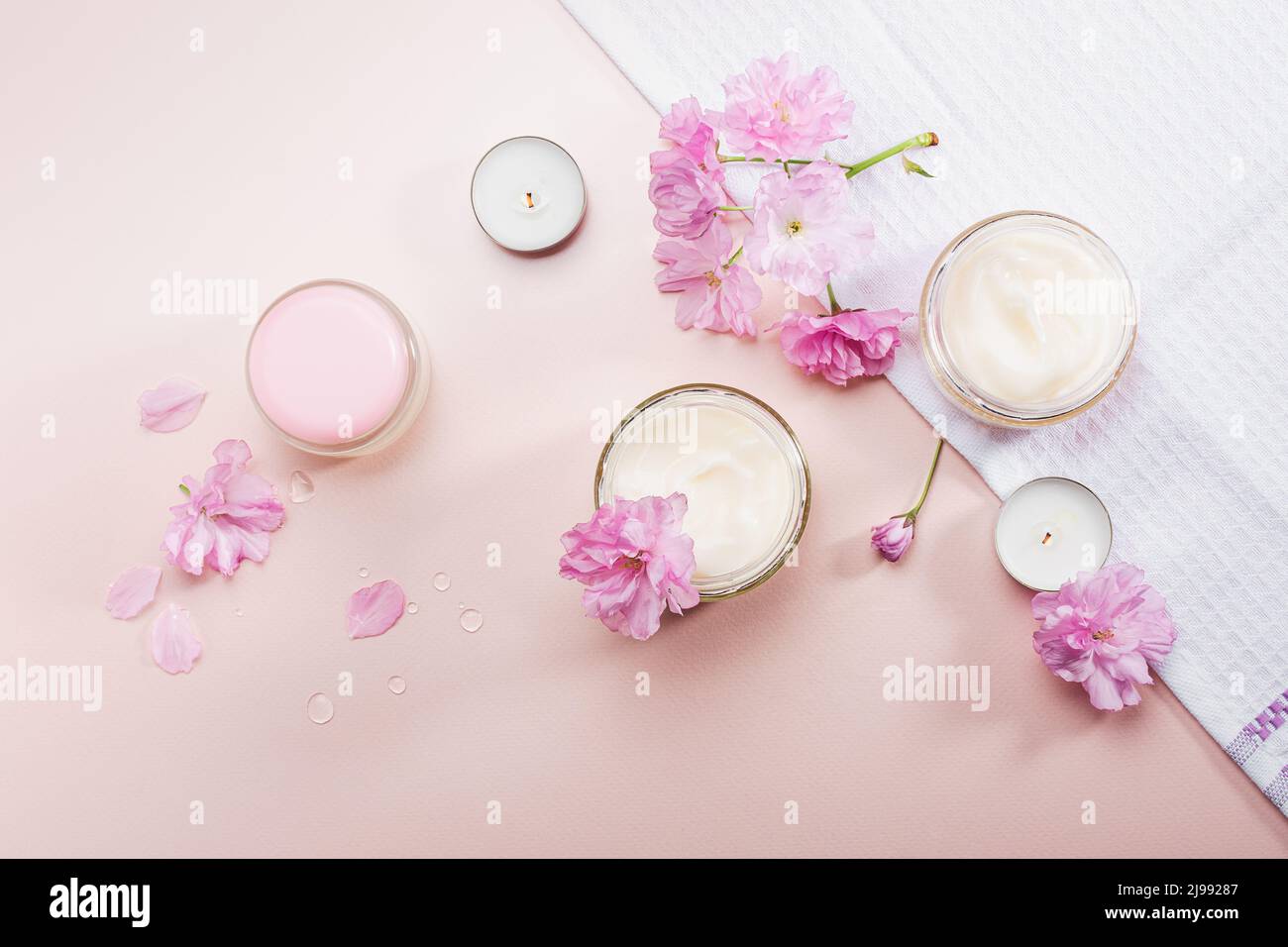 Crème de soin du corps et fleurs de cerisier rose. Pose à plat. Banque D'Images