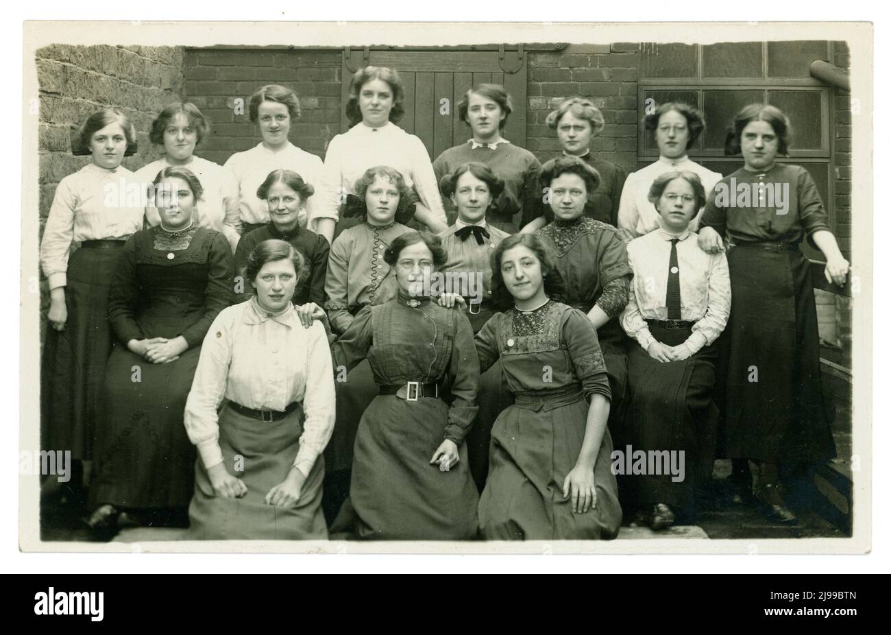 Original et clair WW1 ans groupe en plein air portrait de filles de moulin de textile à argiles Mill. Ils sont soit des opérateurs de l'usine portant leur dimanche meilleur ou le personnel de bureau. Beaucoup de chemisiers et de vêtements de jupe différents de l'époque. Trois des filles portent des badges, peut-être ceux de la compagnie "sur le service de guerre". Les filles travaillent dans la fabrication - peut-être des lainages ou des textiles de coton. Clay's Mill, Halifax, Yorkshire, Angleterre, Royaume-Uni vers 1915 ,1916 Banque D'Images