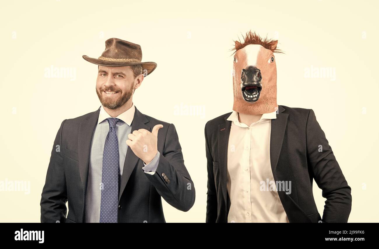 Homme heureux point doigt à l'homme d'affaires étrange portant le masque de tête de cheval dans les vêtements de formalwear, partie occidentale Banque D'Images