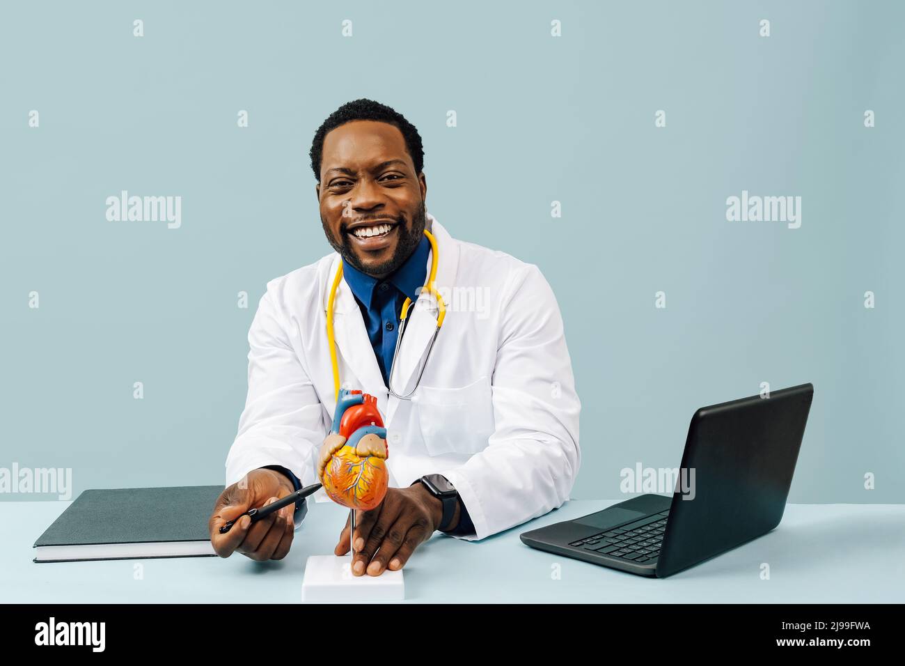 Médecin noir avec modèle de coeur et un stéthoscope isolé sur fond rose studio Banque D'Images