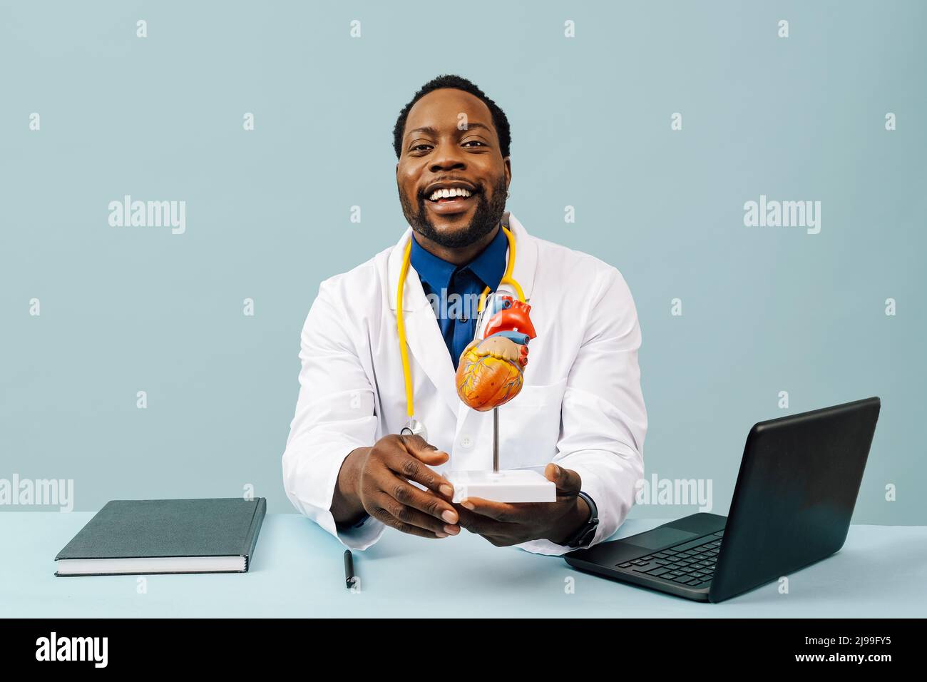 Médecin noir avec modèle de coeur et un stéthoscope isolé sur fond rose studio Banque D'Images