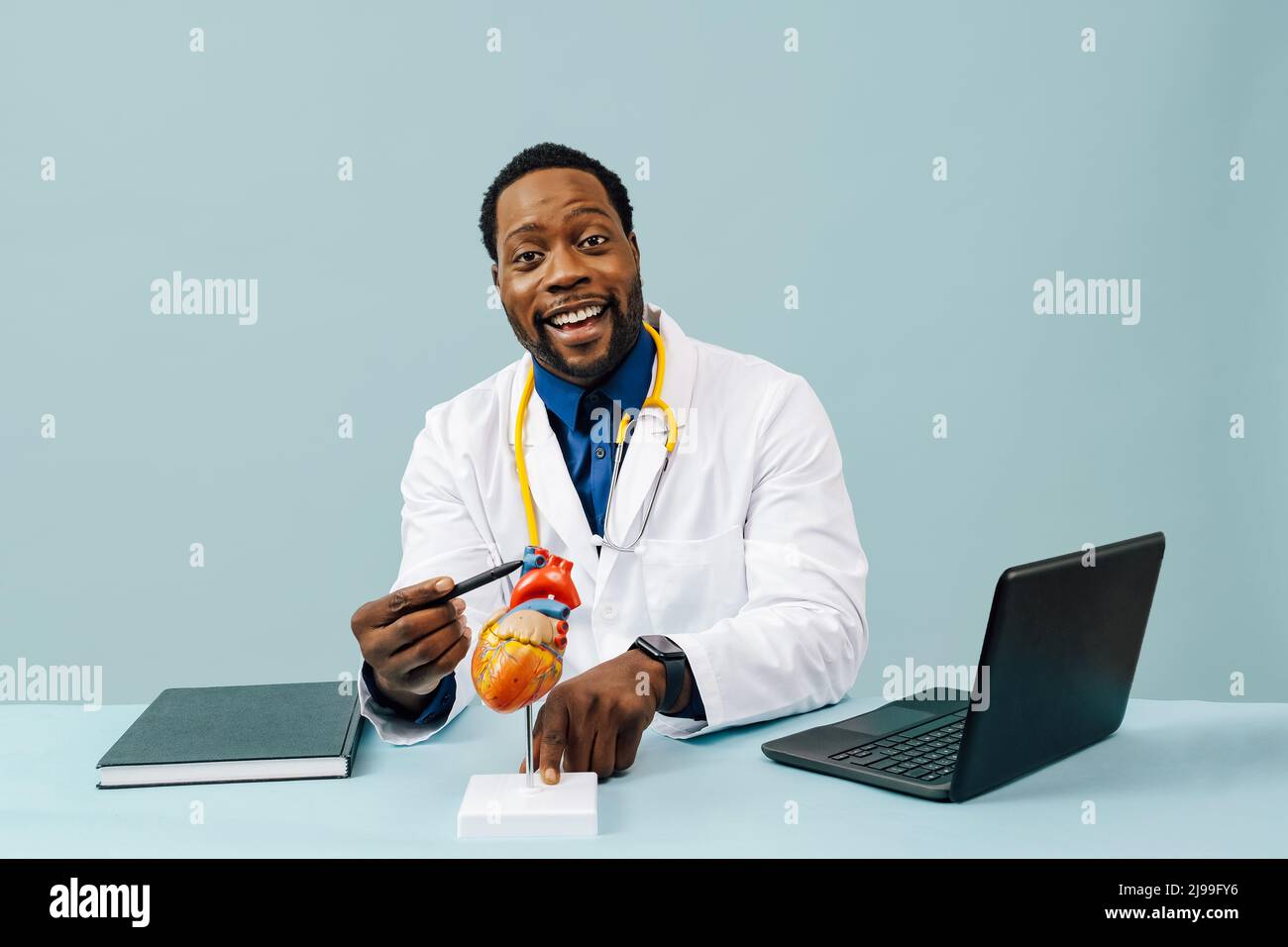 Médecin noir avec modèle de coeur et un stéthoscope isolé sur fond rose studio Banque D'Images