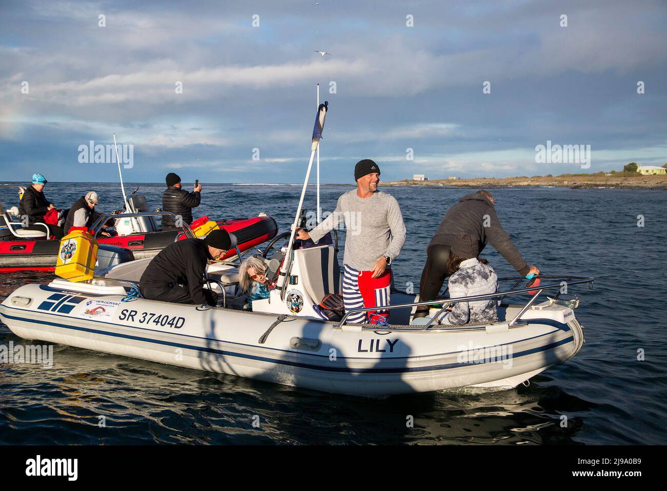 (220522) -- LE CAP, 22 mai 2022 (Xinhua) -- l'homme sud-africain Howard Warrington (2nd R) se prépare à nager dans la mer de l'île Robben à la rive du Cap, en Afrique du Sud, le 21 mai 2022. L'homme sud-africain Howard Warrington a achevé samedi matin son passage en mer de 100th de la célèbre île Robben à la rive du Cap, pour recueillir des fonds pour Cape of Good Hope SPCA (Société pour la prévention de la cruauté envers les animaux), une organisation de protection des animaux. (Photo de Francisco Scarbar/Xinhua) Banque D'Images