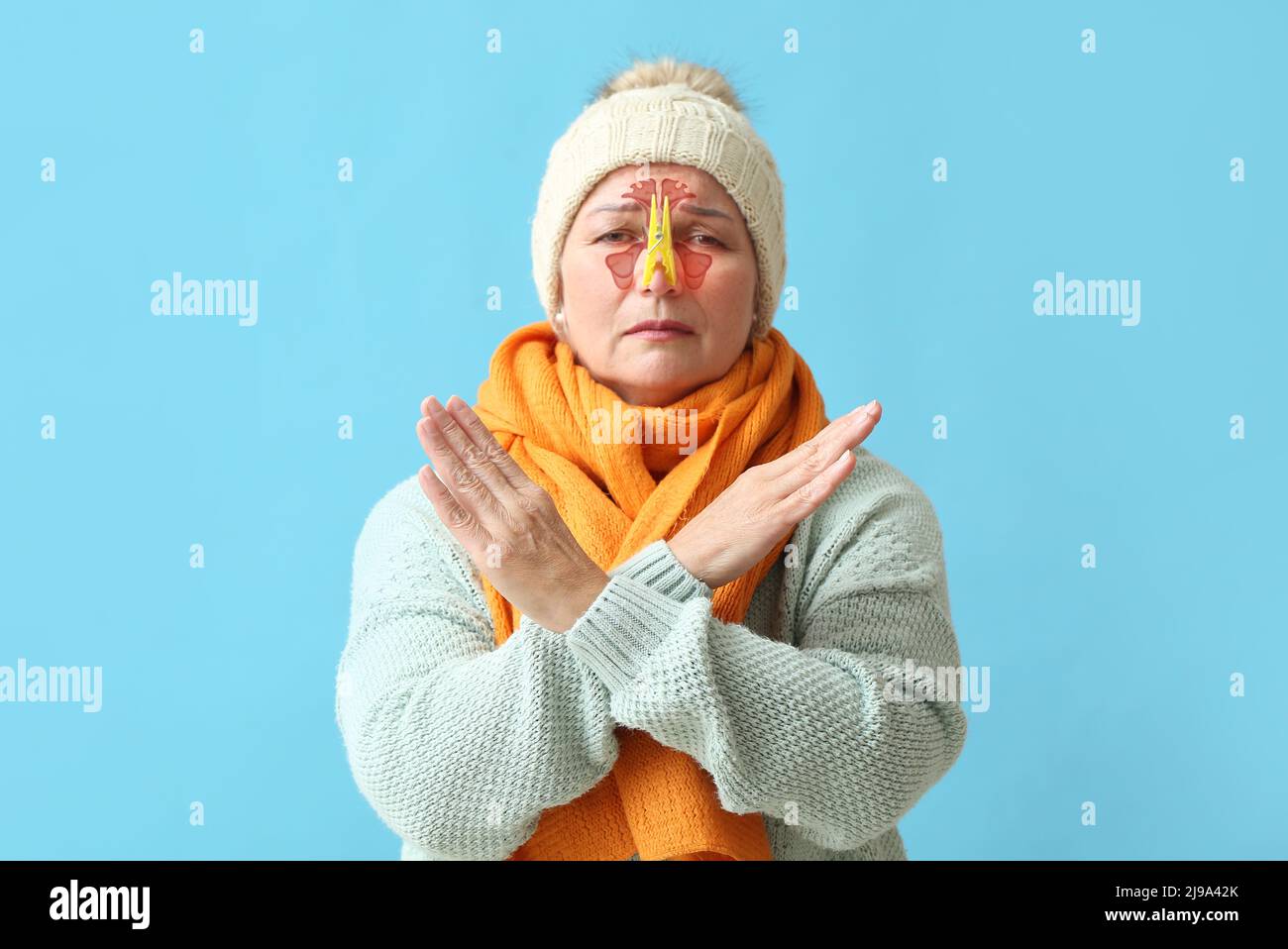 Femme atteinte de maturité avec une épingle à linge sur son nez, sur fond bleu clair Banque D'Images