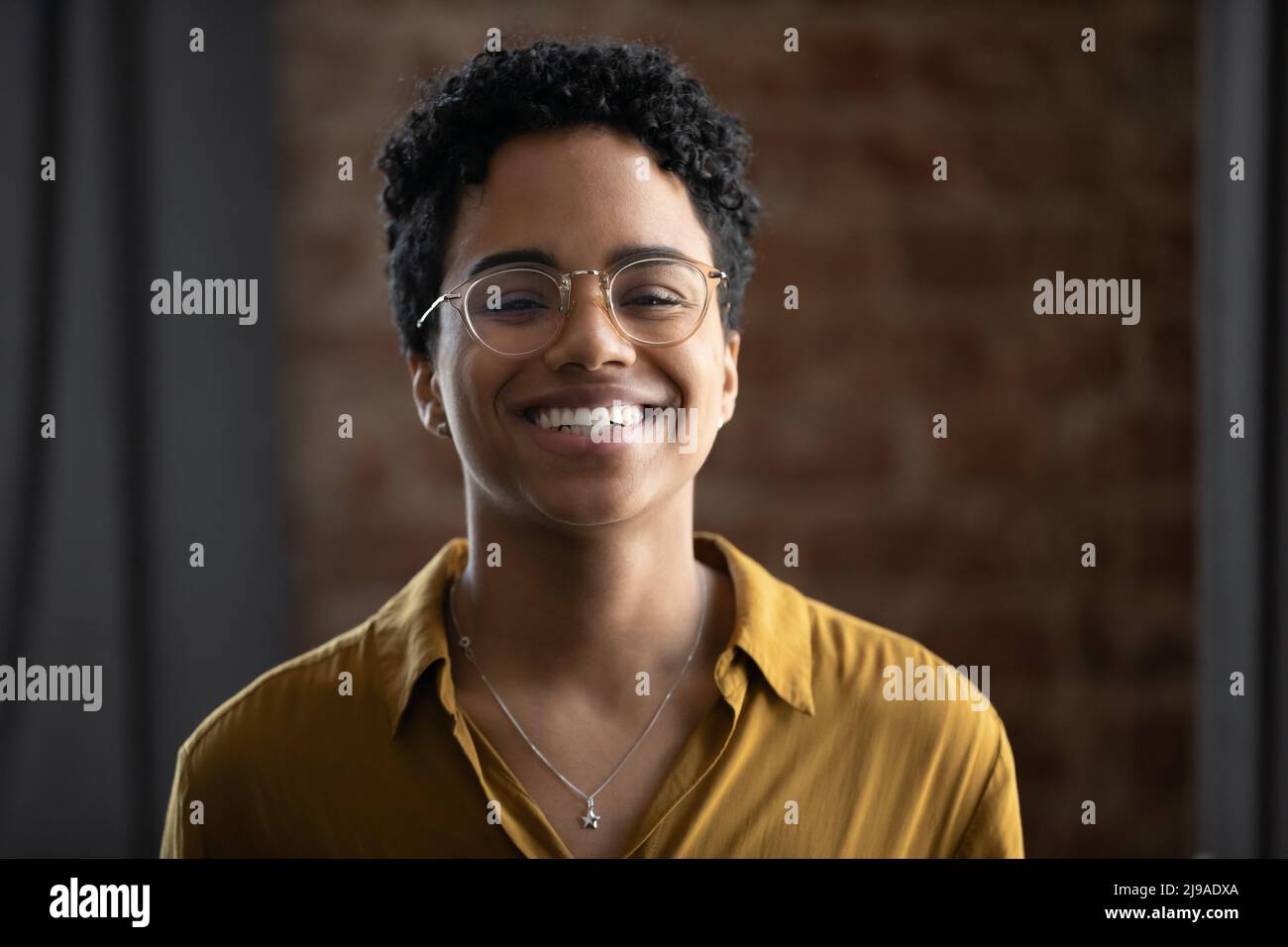 Femme africaine en lunettes ayant le sourire charmant pose pour l'appareil photo Banque D'Images