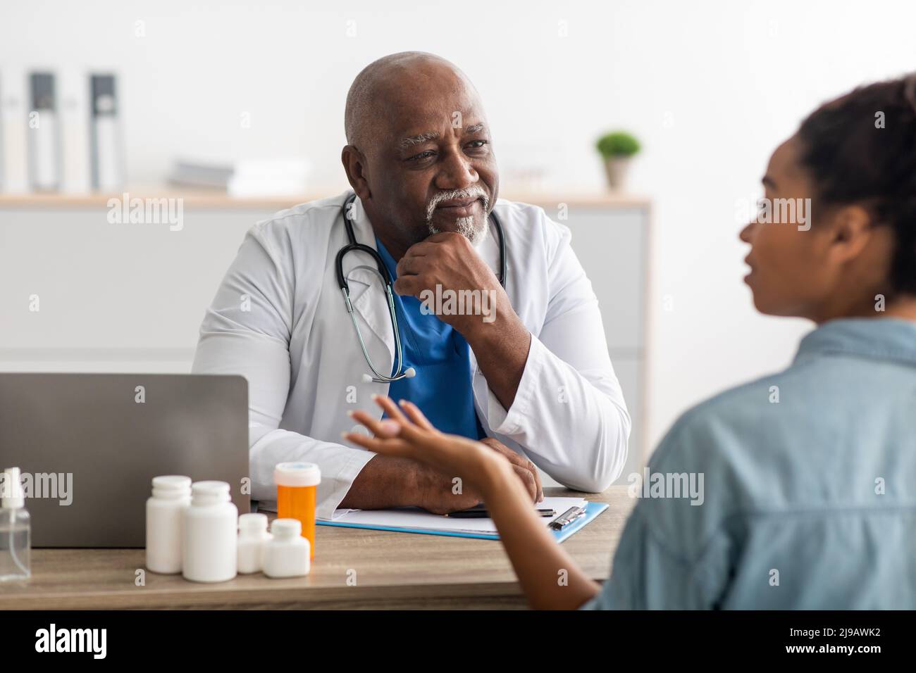 Médecin noir mature à l'écoute de jeunes femmes Banque D'Images Médecin noir mature à l'écoute de jeunes femmes Banque D'Images