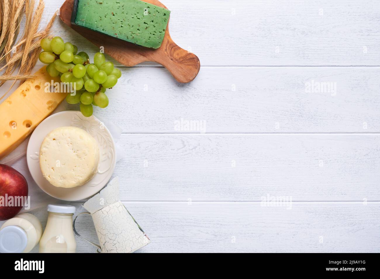 Fête juive de Shavuot. Lait et fromage, blé mûr et fruits, crème. Produits laitiers sur fond de bois blanc. Concept Shavuot. Haut v Banque D'Images