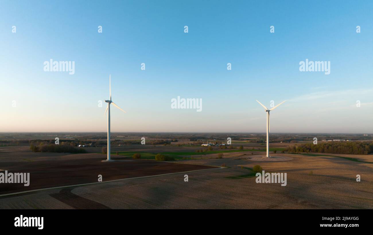 Une paire d'éoliennes sont vues dans un paysage rural, tard dans un ciel clair après-midi. Banque D'Images
