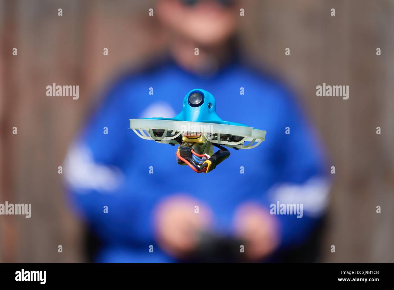 Le petit drone également la course quad en bleu est précisément contrôlée par le pilote humain, mur en marron comme fond.Allemagne. Banque D'Images