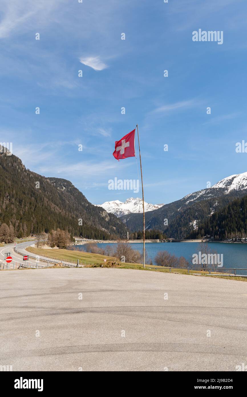 Sufers, Grison, Suisse, 12 avril 2022 agitant le drapeau suisse dans un paysage alpin enneigé sur un beau lac Banque D'Images