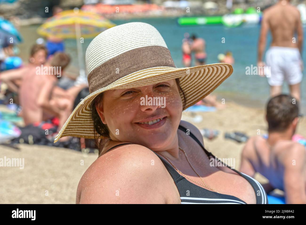 Gros plan été portrait de la tête et de l'épaule d'une jeune femme adulte en relief portant un chapeau de paille sur la plage. Banque D'Images