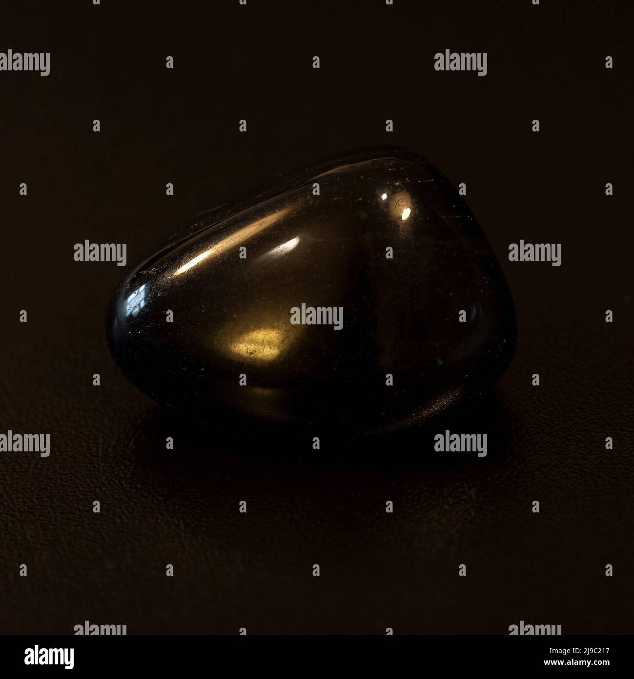 Macro gros plan photo couleur d'un 'Noir obsidienne' poli une pierre précieuse en cristal semi-précieuse utilisée dans la thérapie de guérison de cristal Banque D'Images