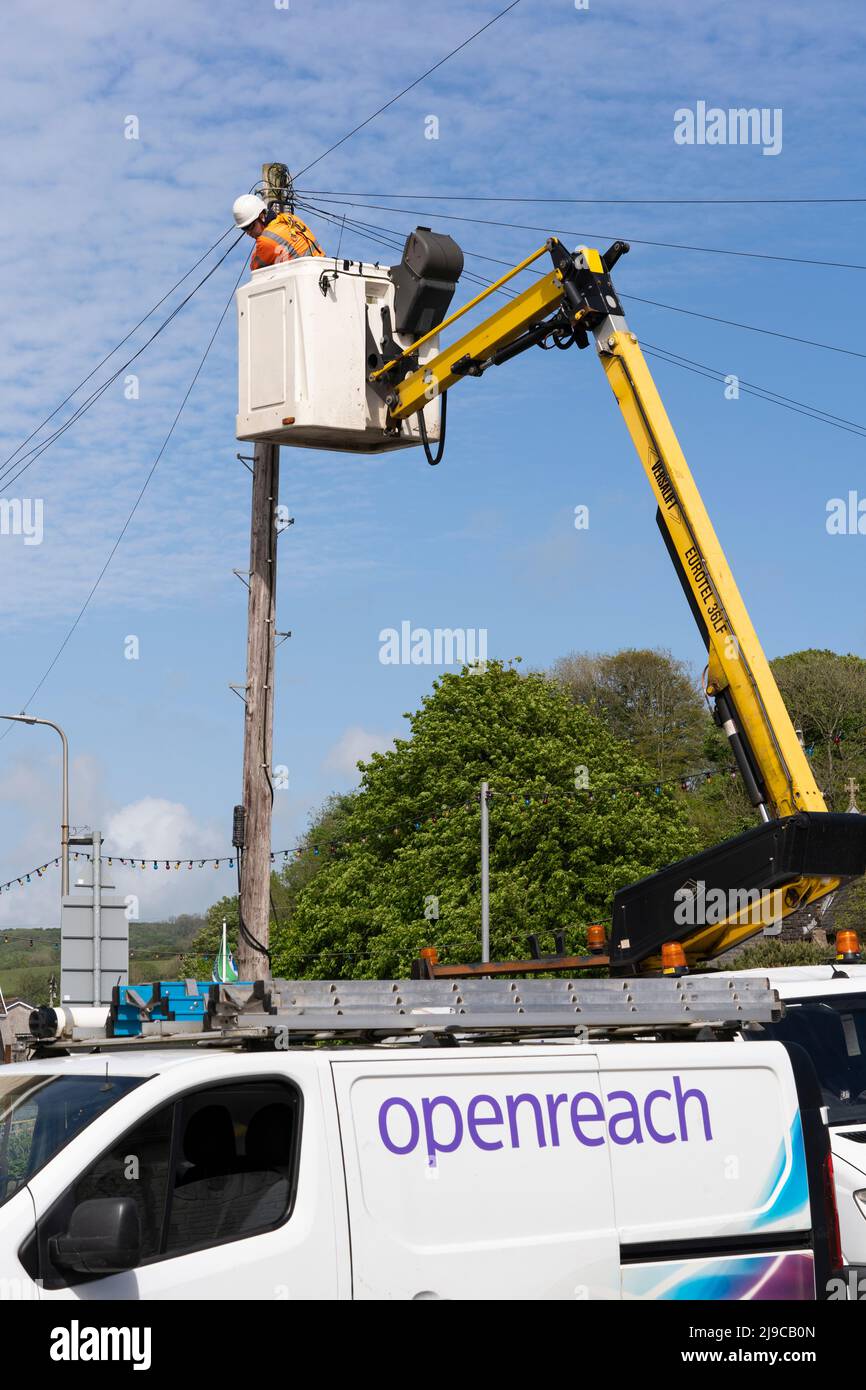 Un technicien de réparation Openreach portant un EPI dans un préparateur de cerisier réparant les câbles téléphoniques aériens sur un poteau téléphonique BT en bois au pays de Galles, au Royaume-Uni Banque D'Images