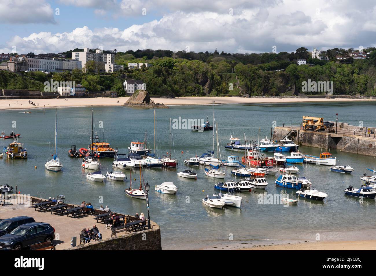 Les gens qui regardent de petits bateaux de plaisance et de pêche dans le port de Tenby avec la plage nord en arrière-plan en mai. Tenby, Pembrokeshire, pays de Galles Banque D'Images