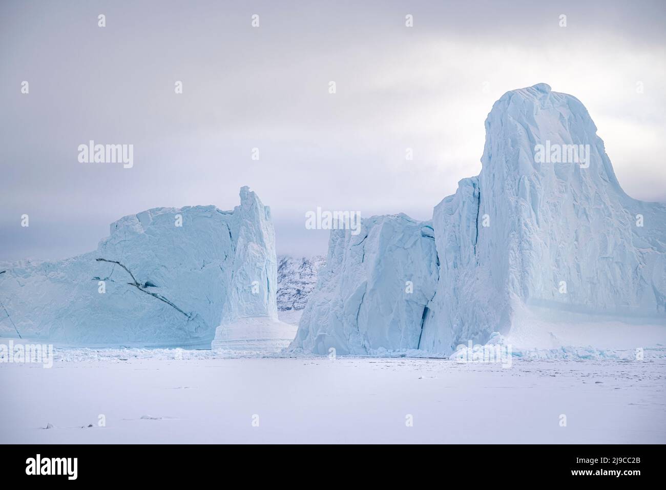 Immense tour de icebergs sur la glace de mer dans le fjord d'Uummannaq, dans le nord-ouest du Groenland. Banque D'Images