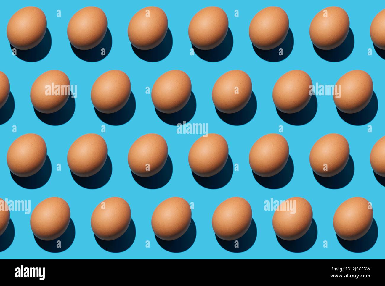 Patron d'œufs de poulet brun crus isolés sur fond bleu. Bonne journée de Pâques. Gros plan, vue de dessus. Banque D'Images