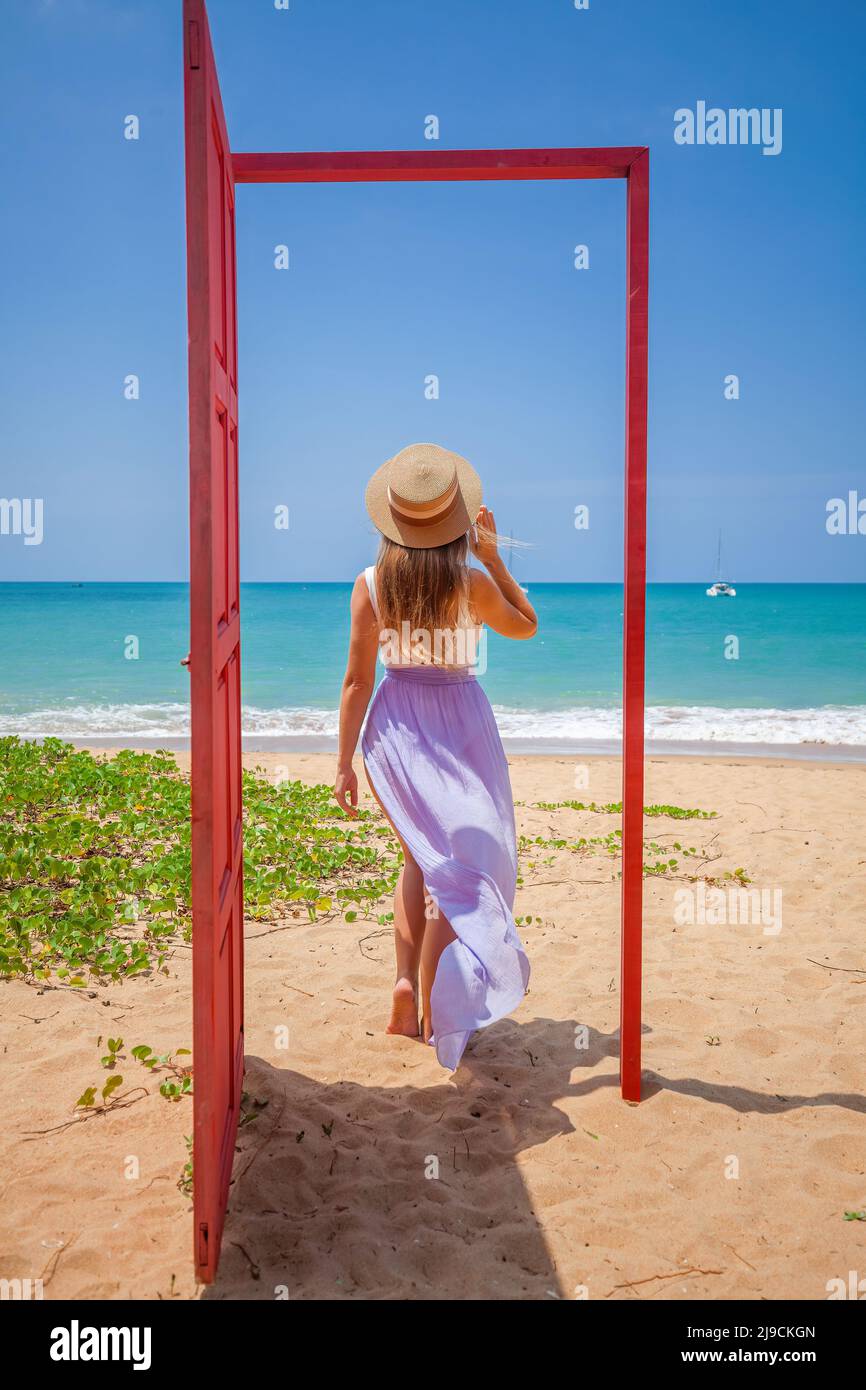 Séjour tropical. Voyageur femme dans la porte rouge sur la plage à la mer turquoise Banque D'Images