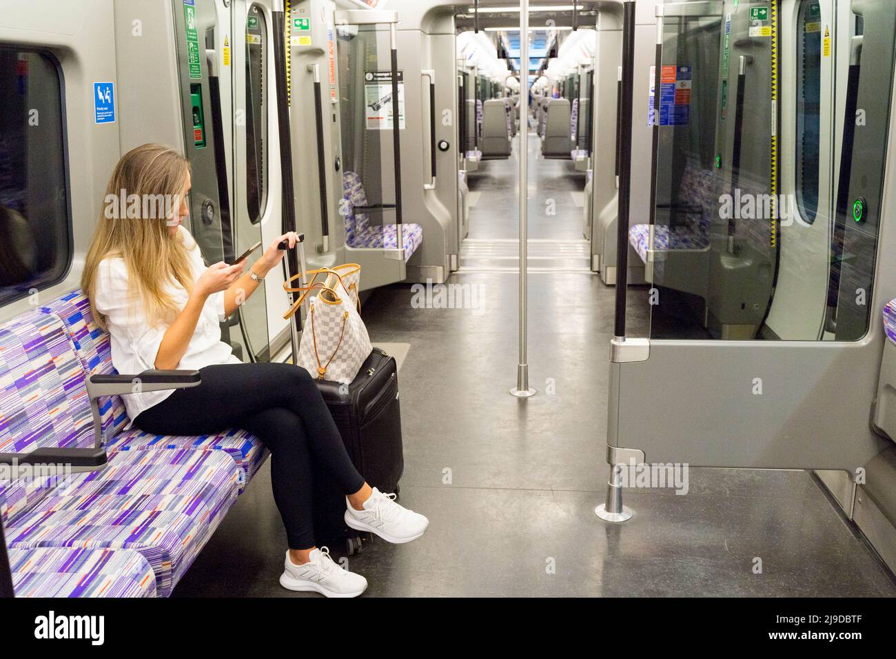 Femme passager assis sur un siège violet à cheval Elizabeth Line , crossrail, ligne violette Londres Angleterre Royaume-Uni Banque D'Images