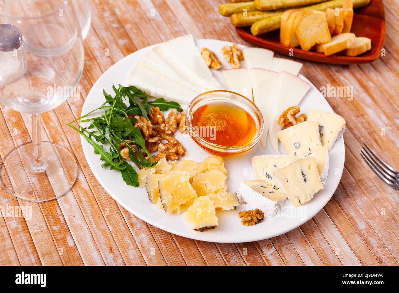 Différents types de fromage tranchés et servis sur une assiette avec un bol de miel, des noix Banque D'Images