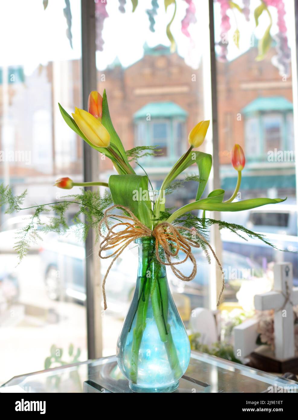 Des tulipes aux couleurs vives dans un joli vase bleu se trouvent dans une fenêtre ensoleillée. Banque D'Images