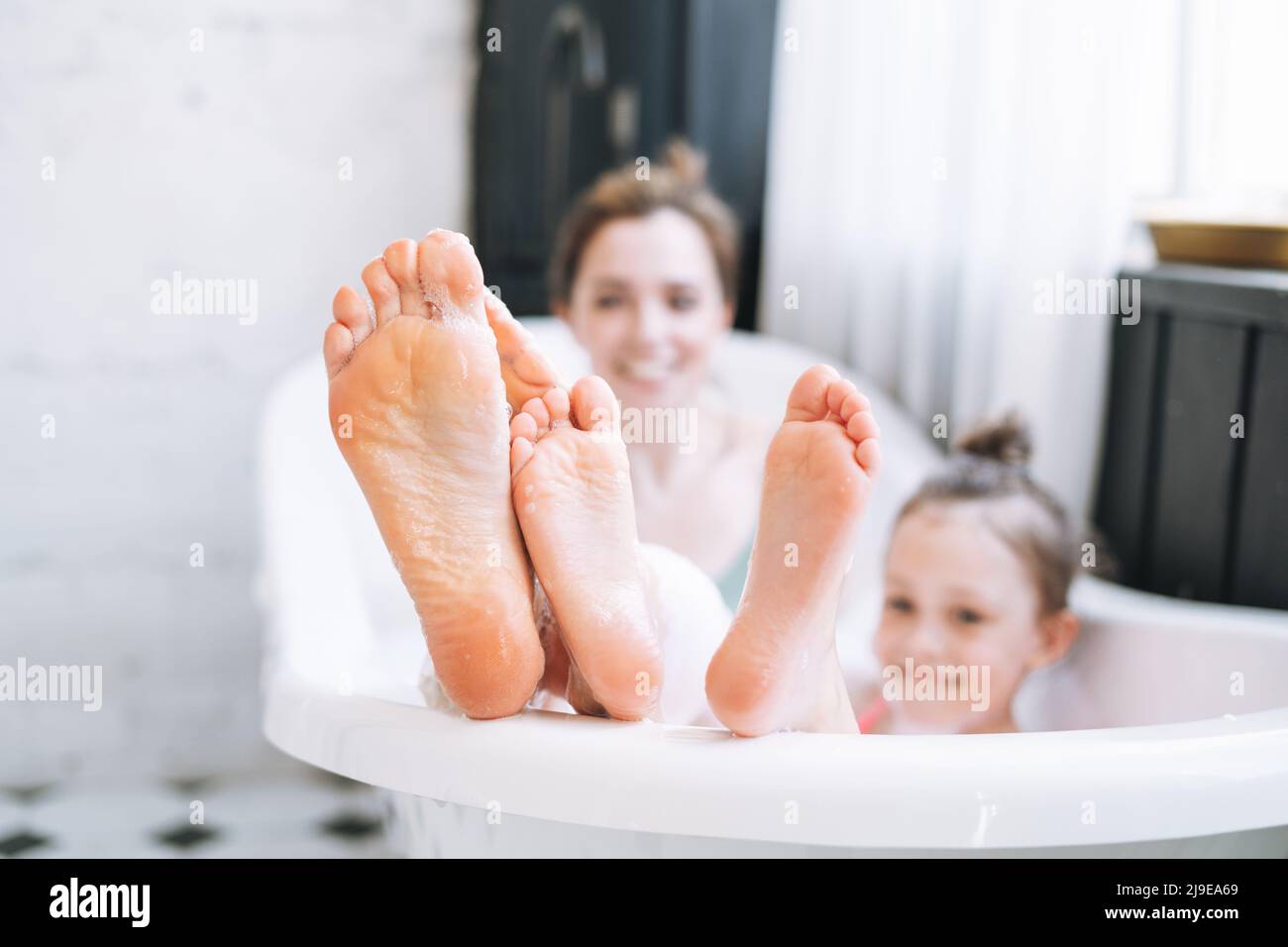 Jeune mère femme et petite fille Tween s'amusant dans le bain avec de la mousse à la maison Banque D'Images