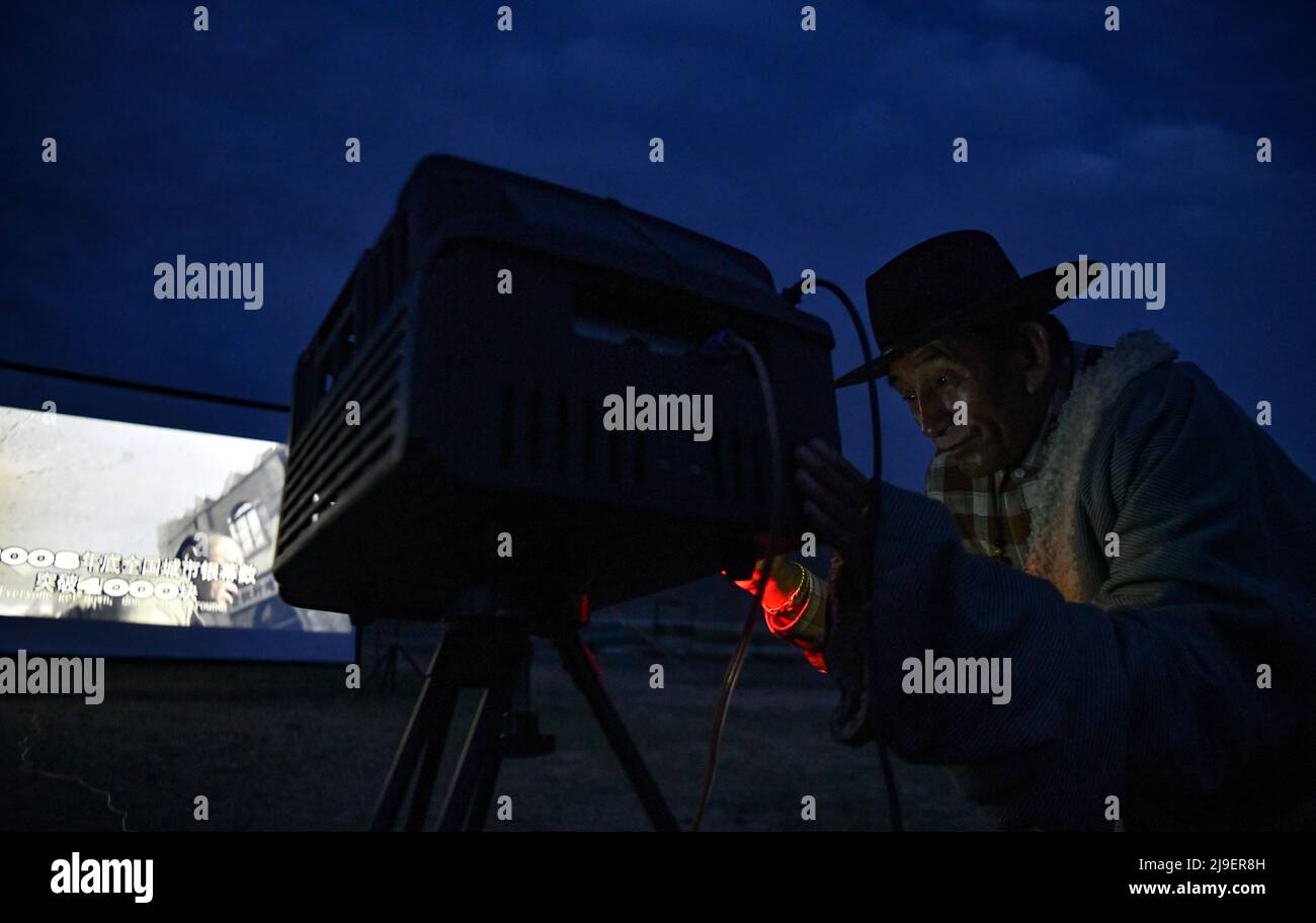 (220523) -- DAMXUNG, 23 mai 2022 (Xinhua) -- Lodro vérifie et trouble-filme le projecteur numérique de film dans le village de Barling, comté de Damxung de Lhassa, région autonome du Tibet du sud-ouest de la Chine, 20 mai 2022. Vivant dans le comté de Damxung à Lhassa, Lodro est un projectionniste rural de cinémas en plein air à but non lucratif. Depuis 1985, Lodro s'est rendu dans près de deux cents villages sur les prairies du nord du Tibet. Pour le public dans les régions éloignées, Lodro a répété des procédures de film-screening encore et encore, en configurant l'écran et la stéréo, en vérifiant et en dépannage le générateur et le projecteur, Banque D'Images