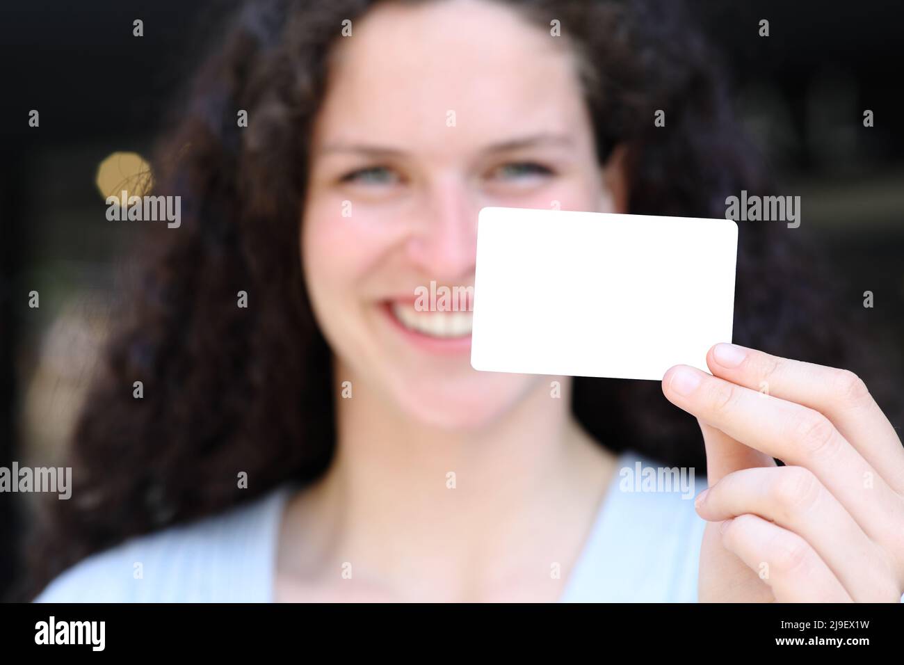 Vue de face Portrait d'une femme heureuse montrant une carte de crédit vierge dans la rue Banque D'Images