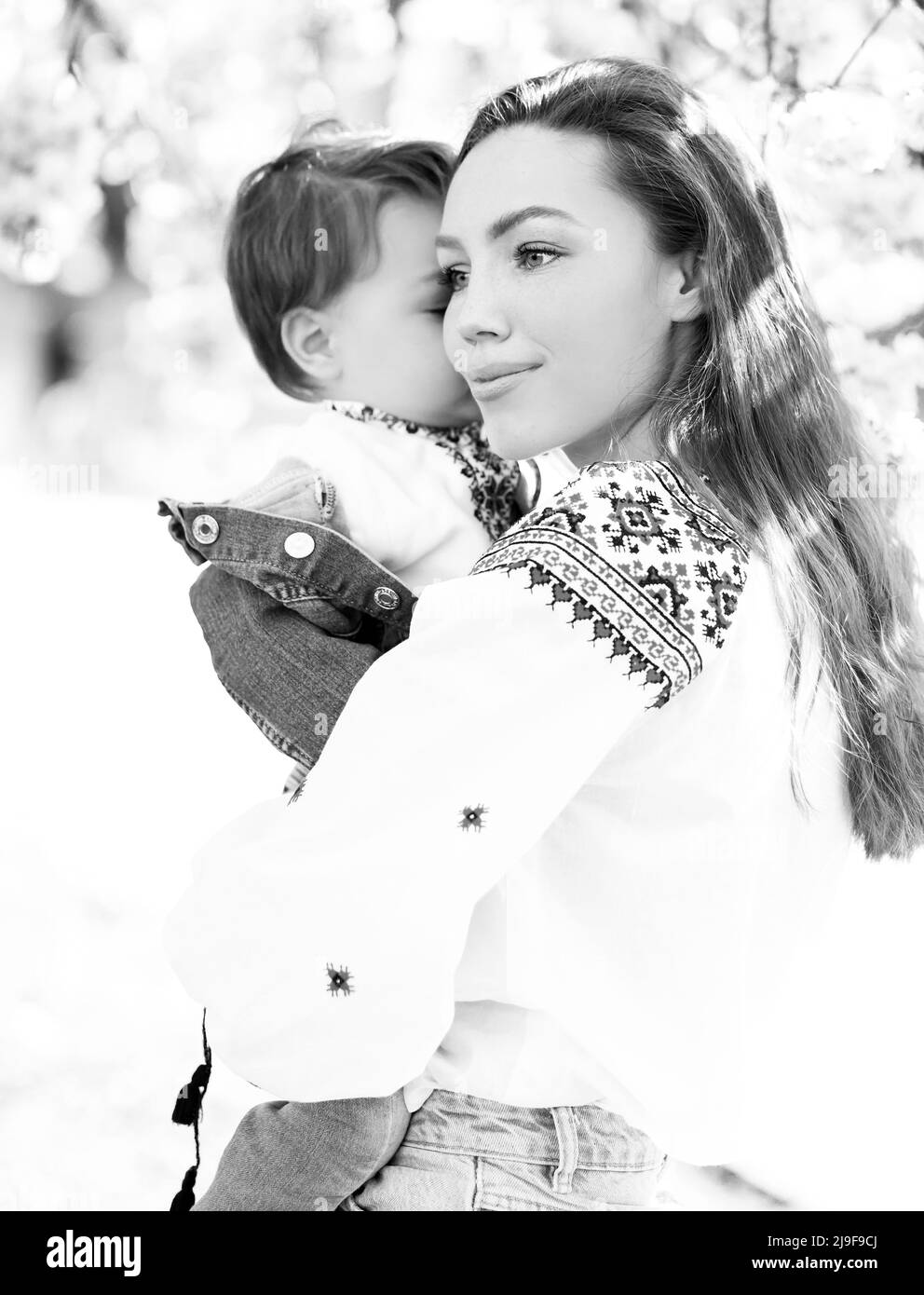 Photo noir et blanc petit bébé sur les mains de la mère. Portrait de famille de deux personnes. Arrière-plan paysage de printemps. Banque D'Images