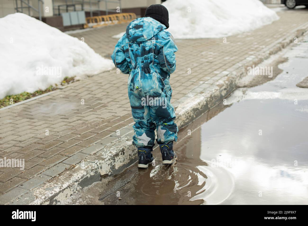 Enfant dans la flaque. Le pré-chooler dans les bottes marche sur l'eau. Bas de porte de printemps. Banque D'Images