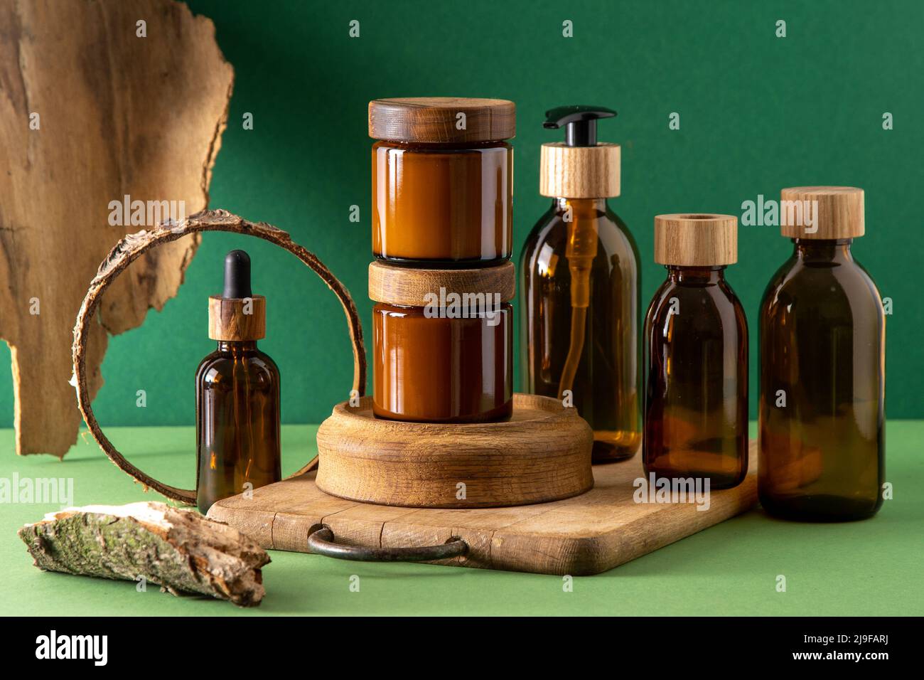 Récipients marron en verre pour cosmétiques avec couvercles en bois. Pot à crème, flacon compte-gouttes et lotion. Arrière-plan vert. Soins et beauté. Bouteilles. Concept écologique. Ensemble de cosmétiques. Pipette et distributeur. Banque D'Images