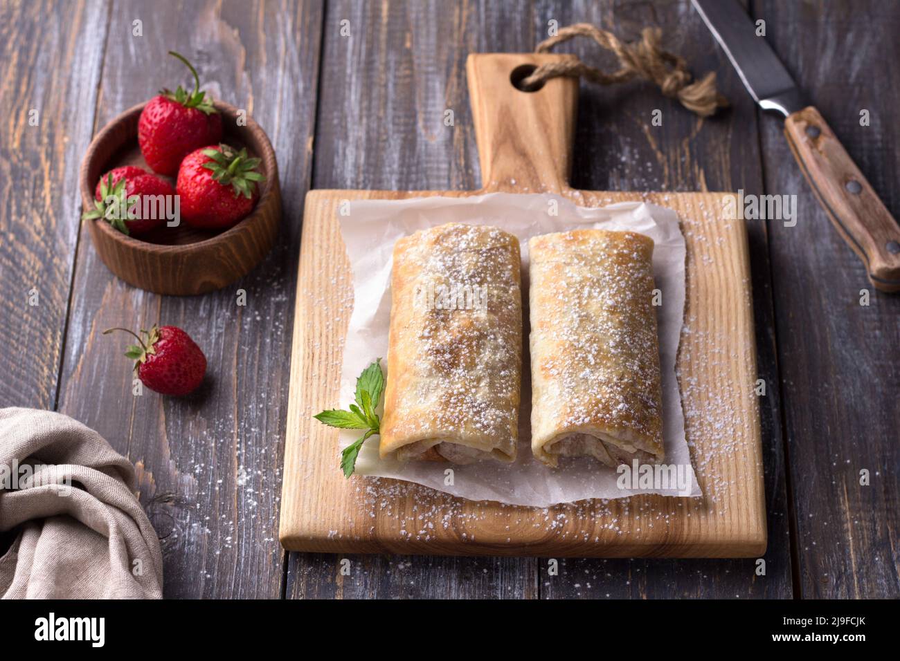 Chimichanga mexicain sucré aux bananes et aux fraises, arrosé de sucre en poudre sur une table en bois. Vue du dessus. Espace Banque D'Images