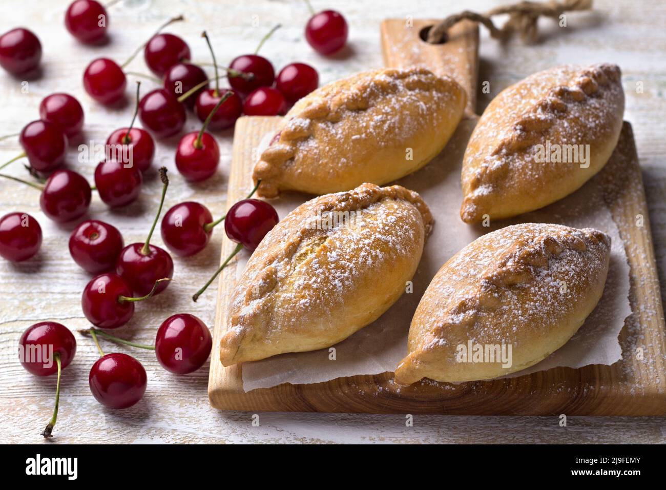 Mini-chaussons faits maison avec cerise et cannelle sur fond de bois Banque D'Images