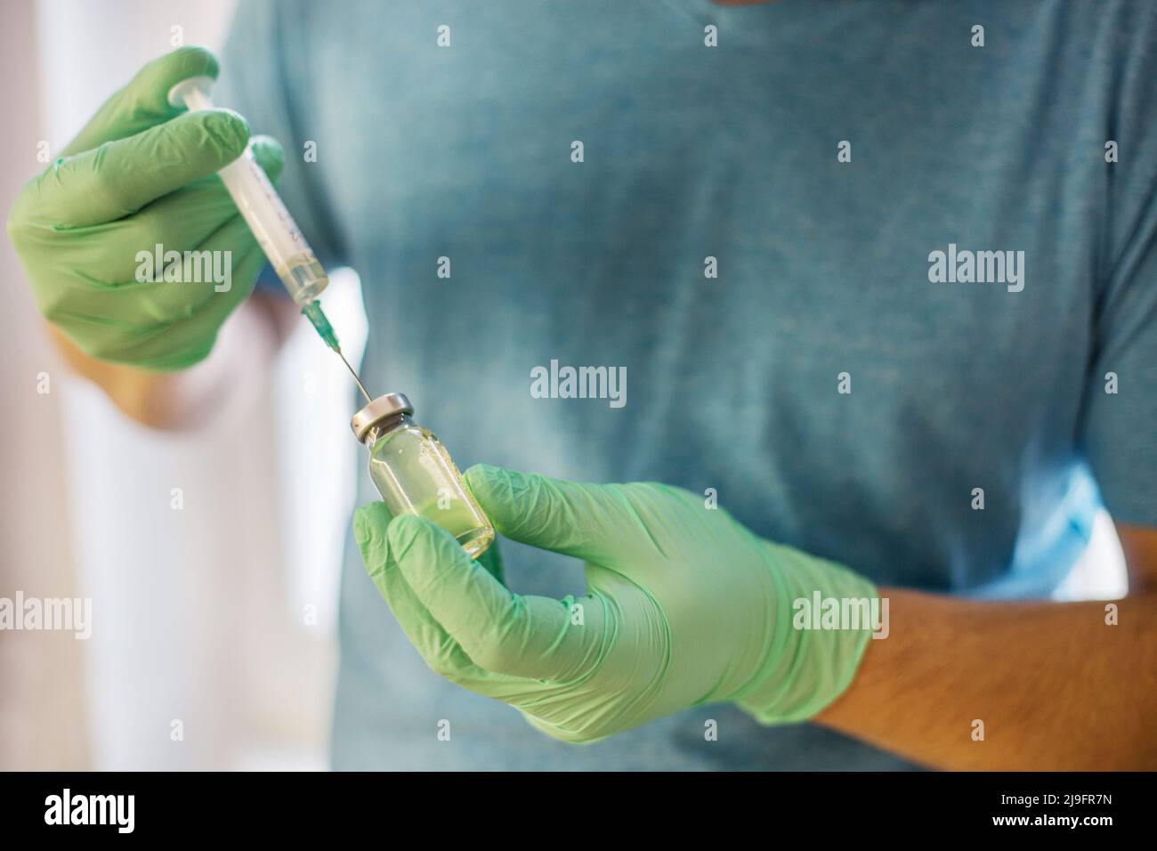 Mains du médecin remplissant une seringue. Homme mains dans des gants bleus tenant le vaccin. Médecine, vaccination et concept de drogue. Médicament flacon dose injection Banque D'Images