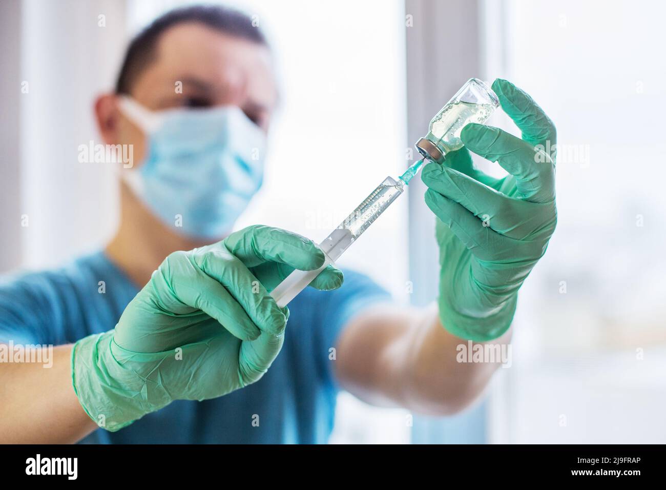 Mains du médecin remplissant une seringue. Homme mains dans des gants bleus tenant le vaccin. Médecine, vaccination et concept de drogue. Médicament flacon dose injection Banque D'Images