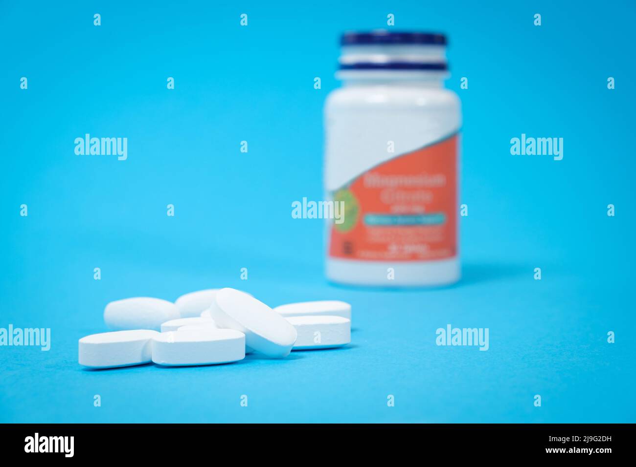 Un pot de suppléments alimentaires et de pilules blanches sur fond bleu, un lieu pour le texte. Vitamines et oligo-éléments pour une alimentation complète Banque D'Images