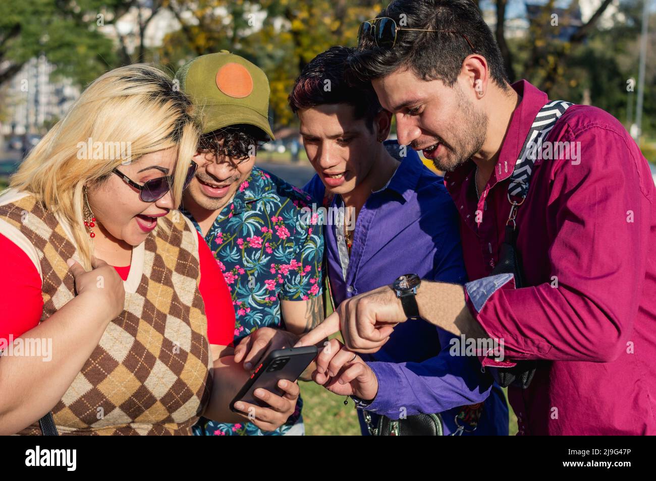 groupe diversifié de jeunes amis caucasiens, en plein air ensemble vérifiant un téléphone, souriant regardant et pointant vers l'écran du téléphone Banque D'Images
