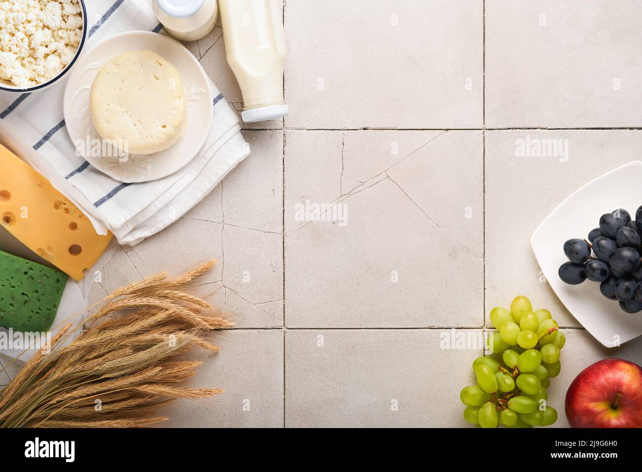 Fête juive de Shavuot. Lait et fromage, blé mûr et fruits, crème vieux panneau fissuré mur fond. Produits laitiers sur fond gris Banque D'Images