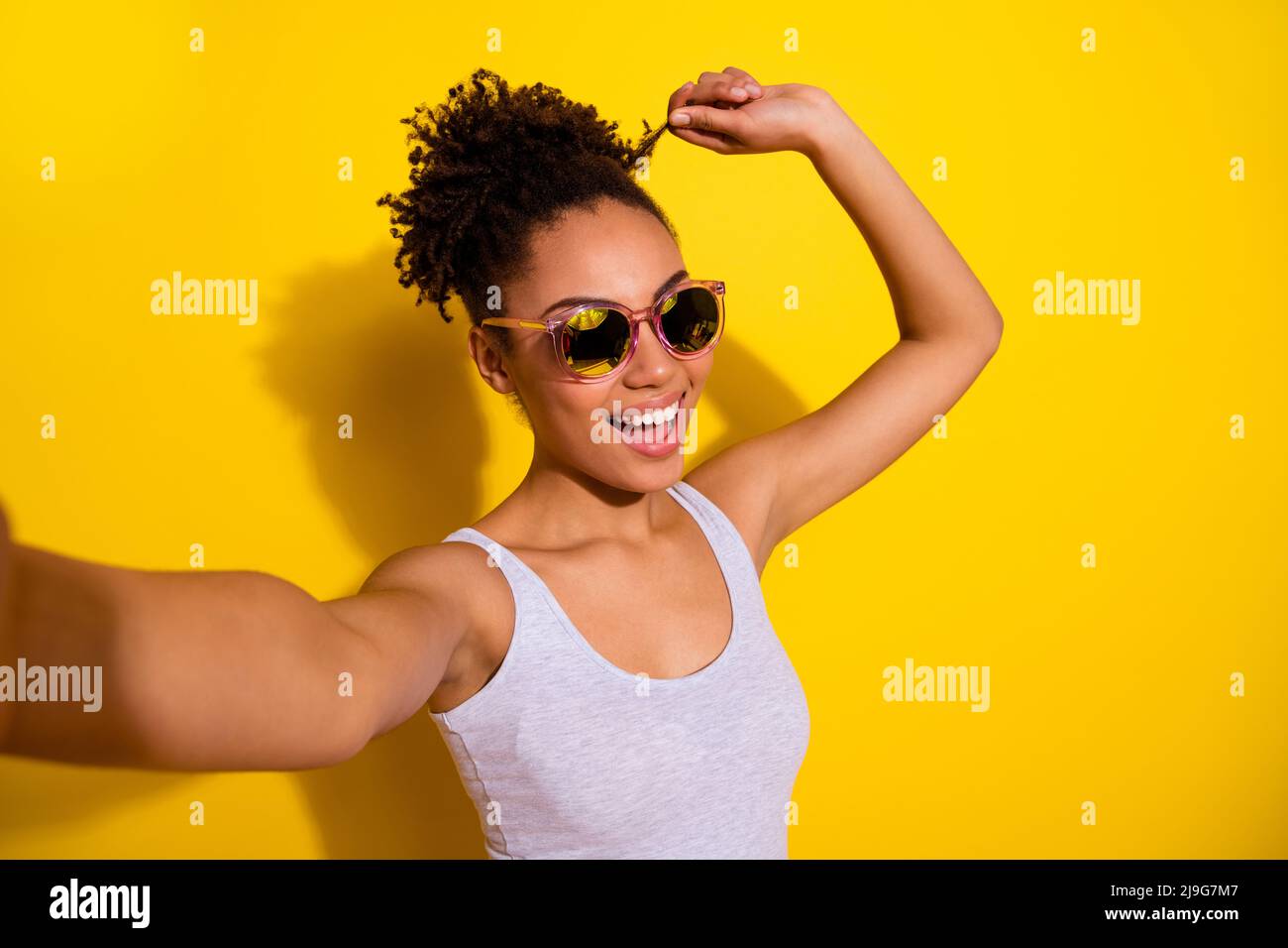 Portrait de gai belle fille bras toucher cheveux curl prendre selfie isolé sur fond jaune couleur Banque D'Images