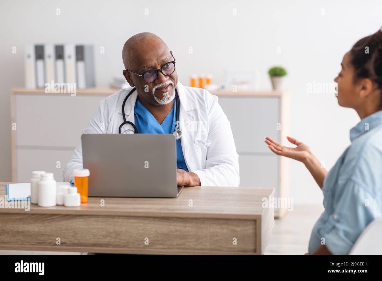 Médecin noir mature à l'écoute de jeunes femmes Banque D'Images Médecin noir mature à l'écoute de jeunes femmes Banque D'Images