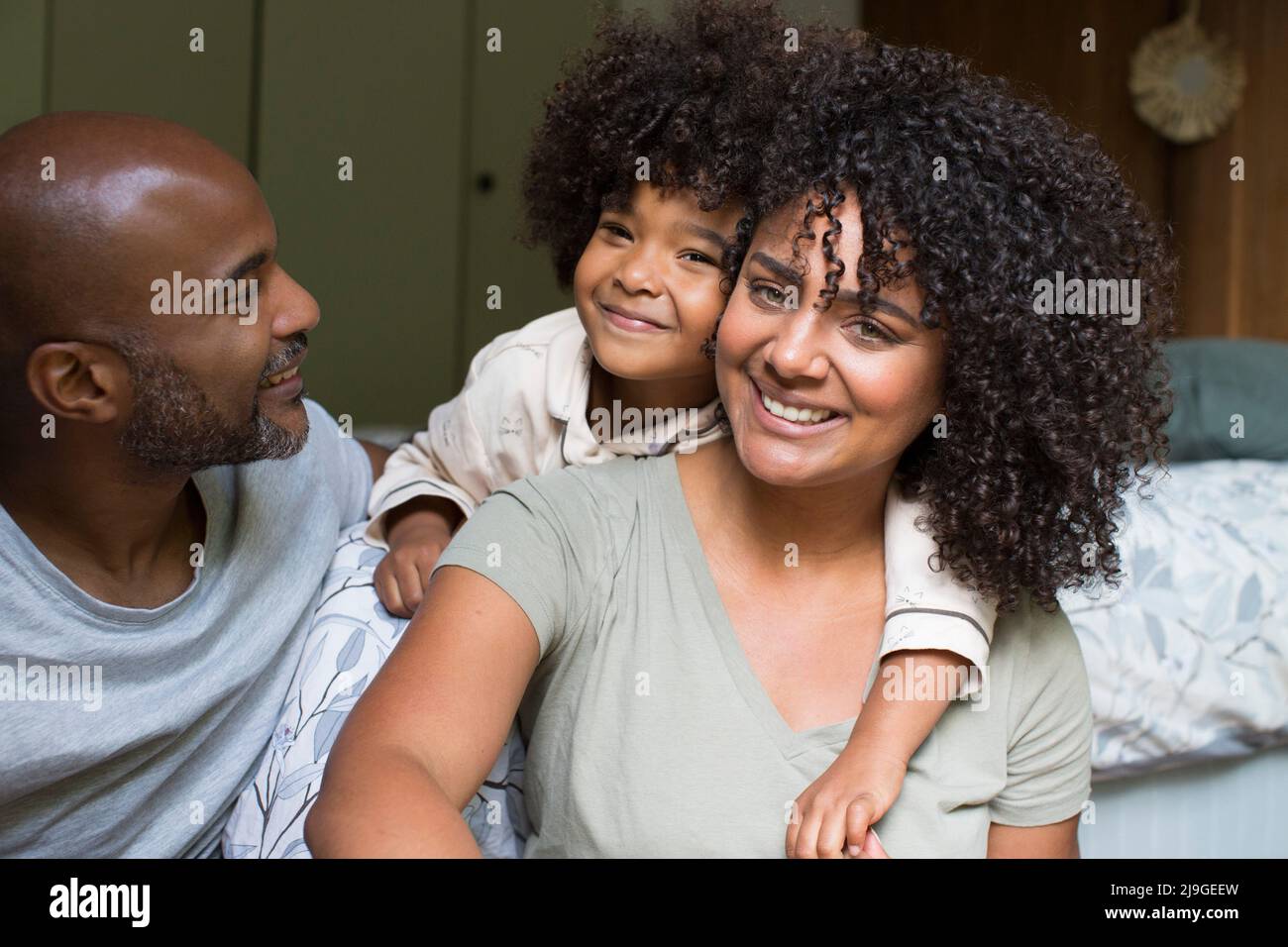 Famille souriante assise sur le lit Banque D'Images
